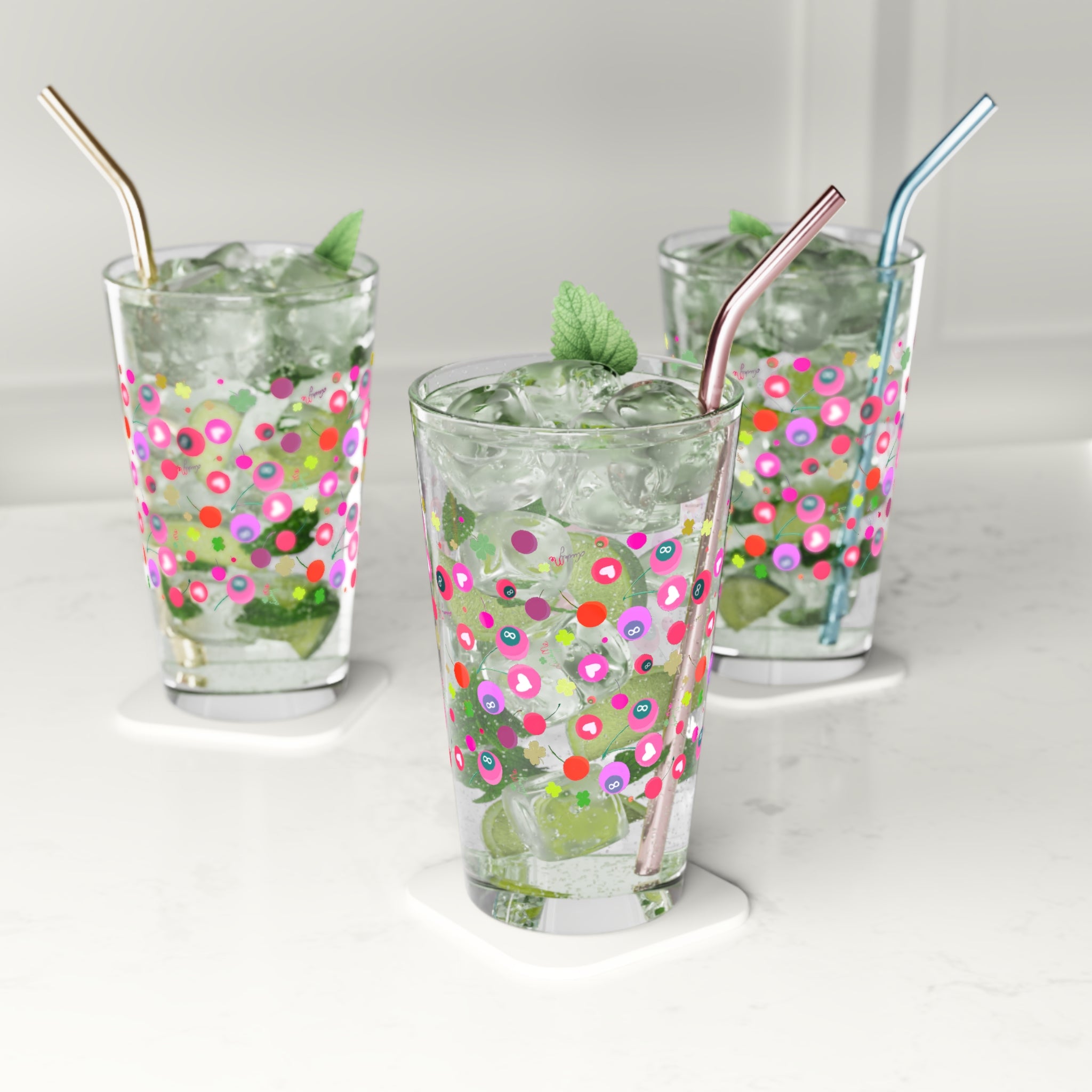 Pint glass with colorful print shown on a table with drinks and ice