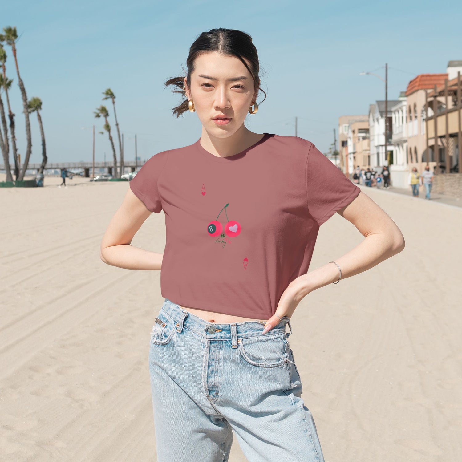 Close-up of the Lucky Me mauve cropped t-shirt, featuring cherries, heart, and ace card symbols, styled with high-waist denim.